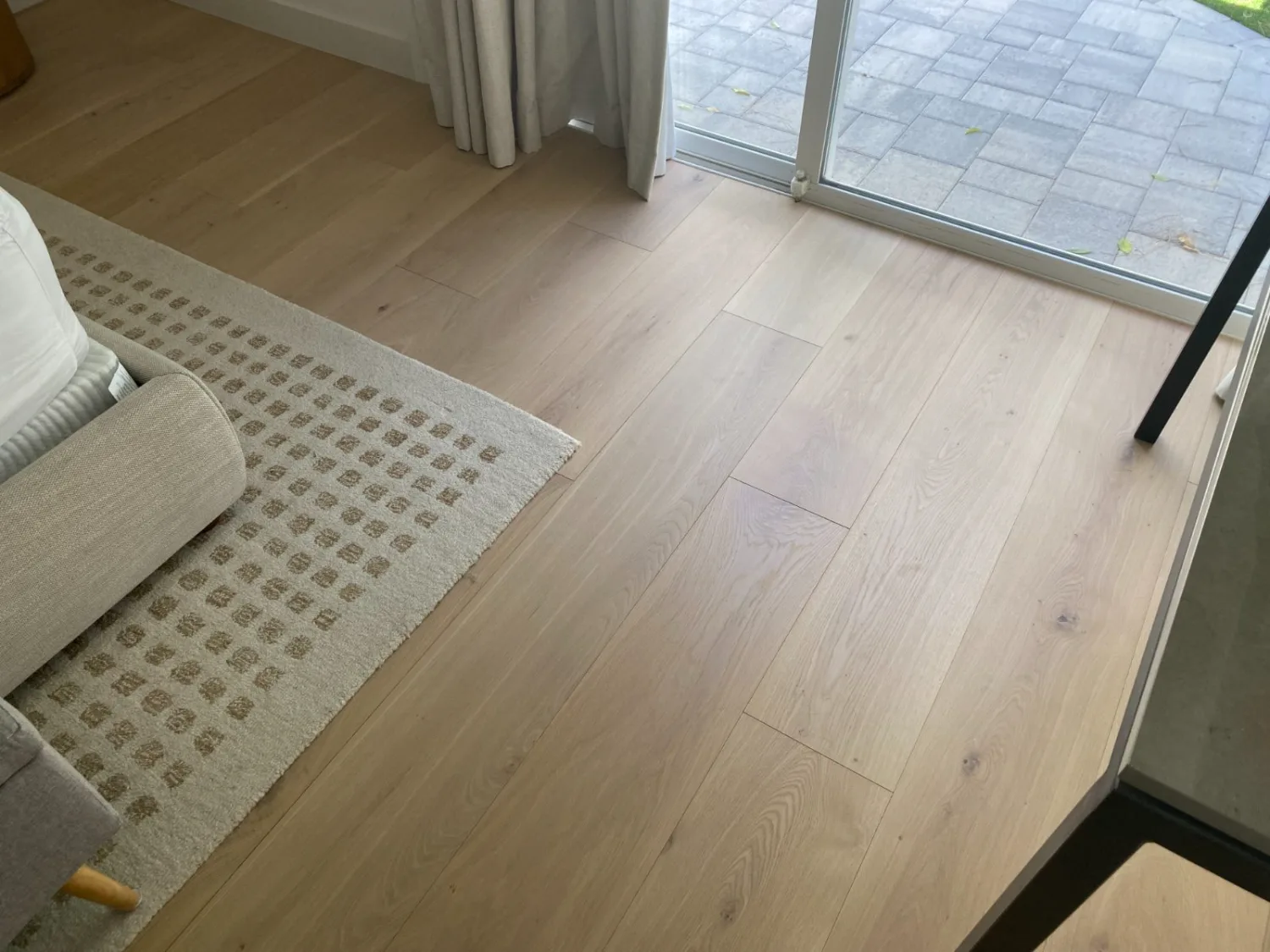 Light oak hardwood flooring by patio doors with an area rug