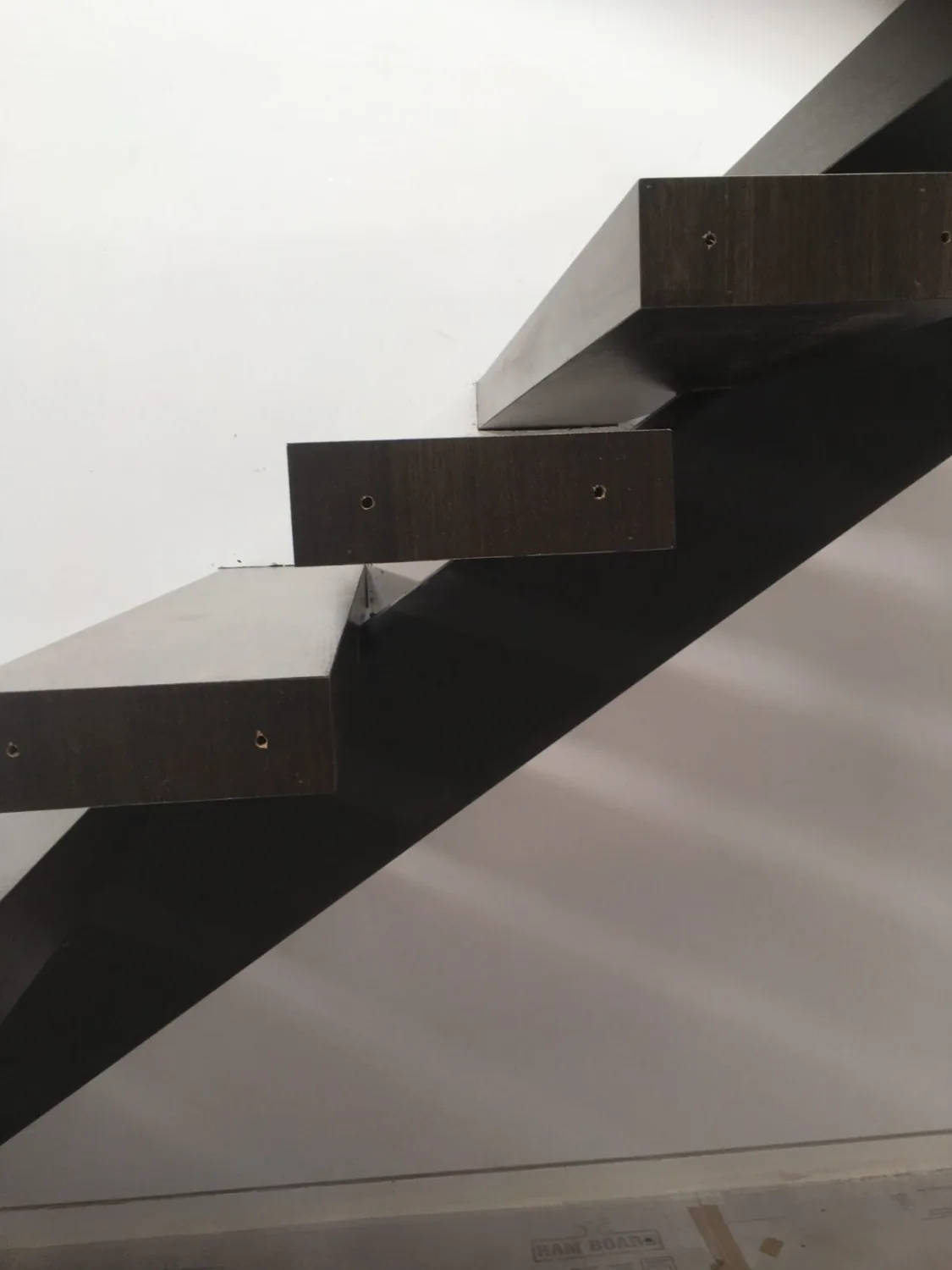 Floating dark-stained hardwood stair treads