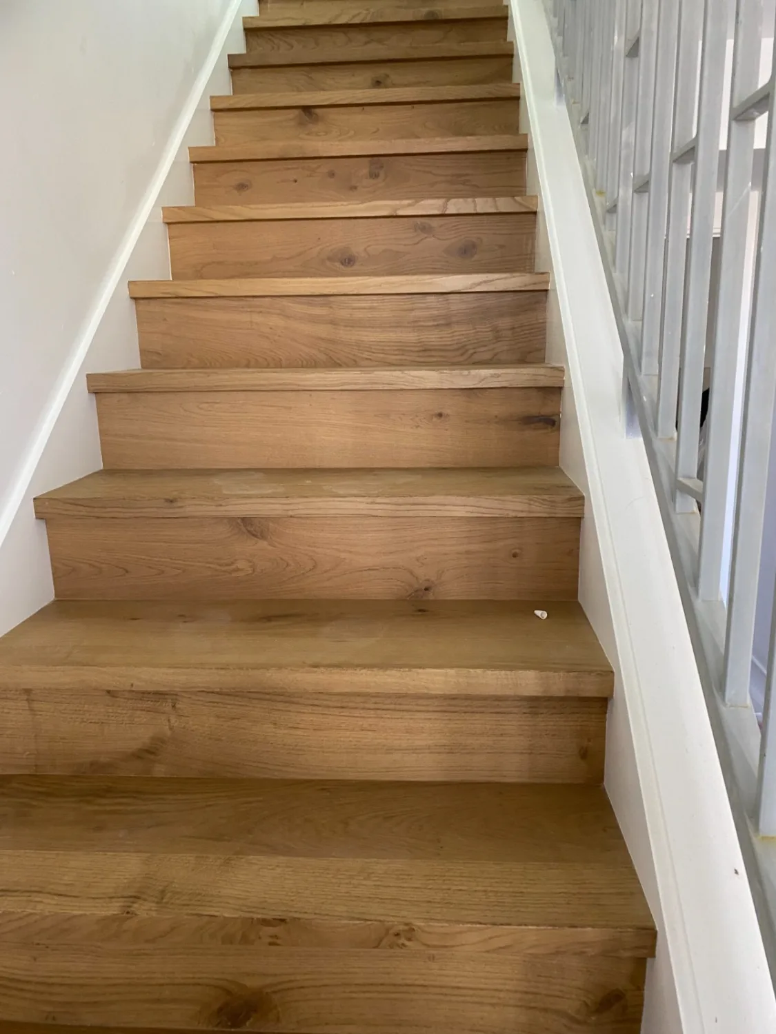 Natural oak hardwood stair treads in a straight flight with a railing