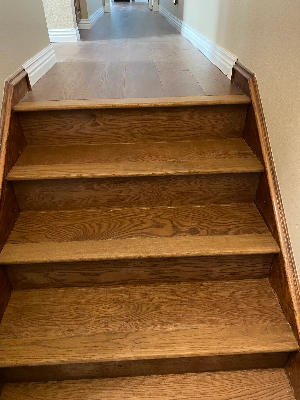 Red oak hardwood stair treads meeting a hallway floor at the landing