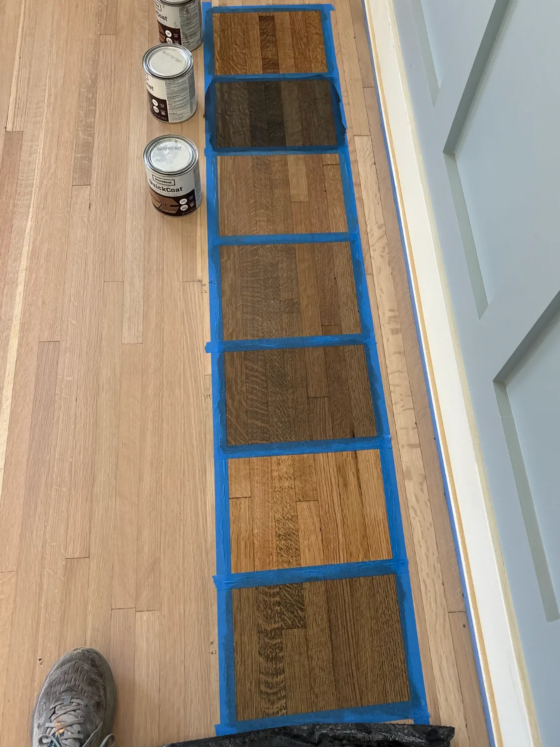 Red oak floor sanded to bare wood with DuraSeal stain color samples taped out to choose a finish